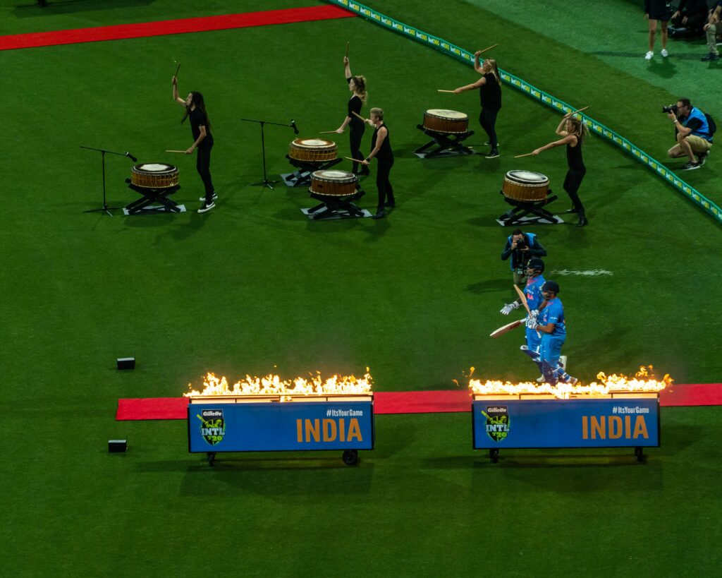 "Indian cricket team celebrating a historic win, fireworks in the stadium, players lifting the bat in joy, scoreboard showing the final victory."