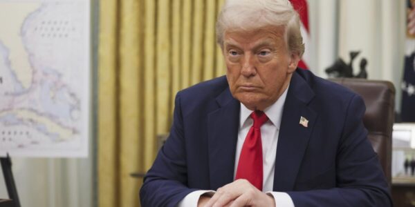 A news graphic featuring former President Donald Trump with a backdrop of shipping containers and financial charts, symbolizing the impact of upcoming tariffs on global trade.